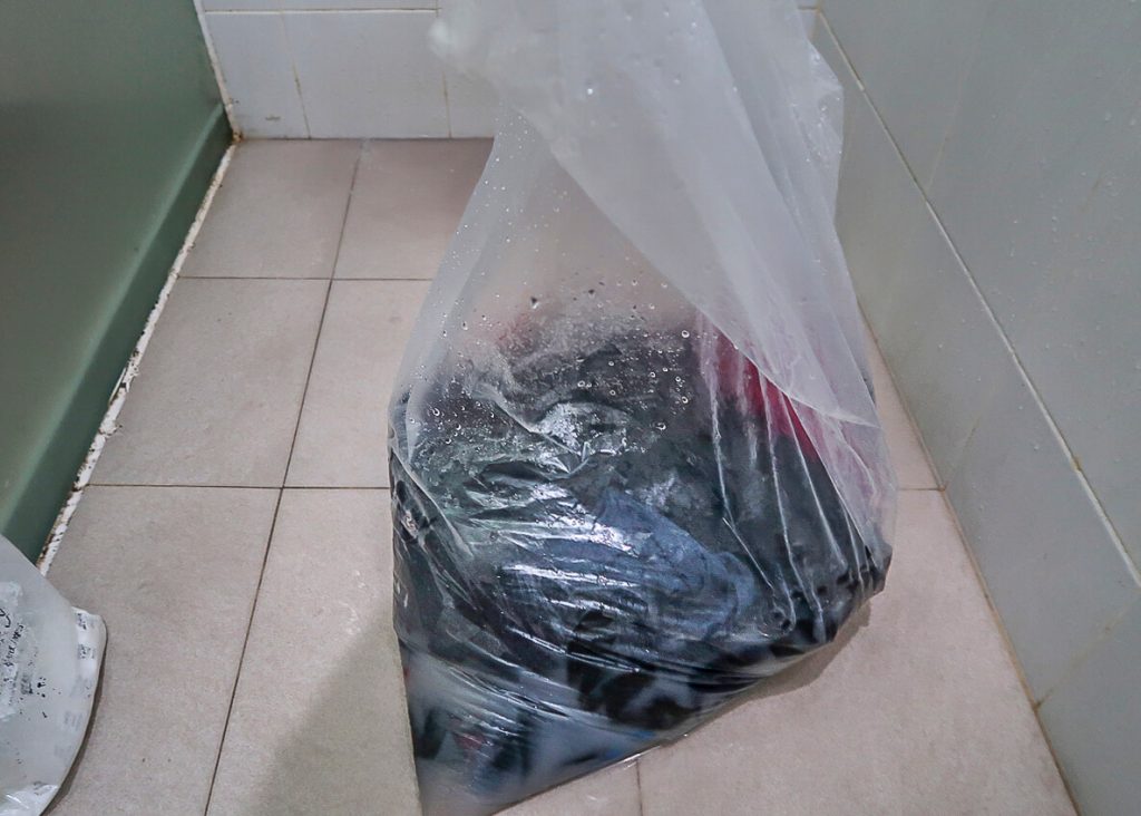 Backpackers washing clothes in bin bag